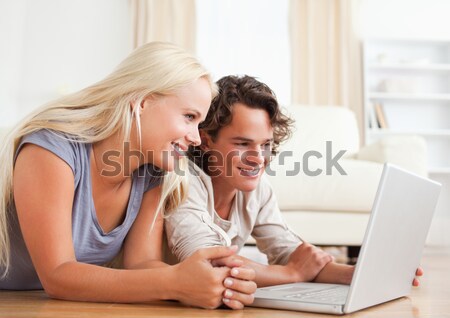 Young couple lying on the floor with laptop booking holidays Stock photo © wavebreak_media