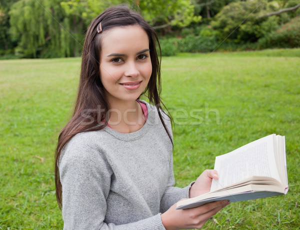 Smiling young girl standing in a parkland while holding a book Stock photo © wavebreak_media