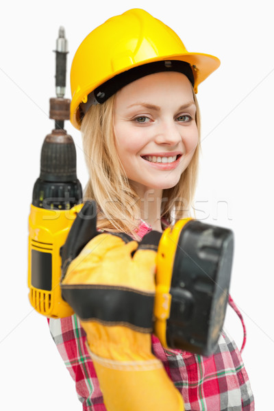 Smiling woman holding an electric screwdriver against white background Stock photo © wavebreak_media