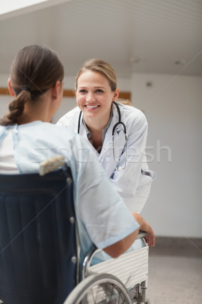 Doctor looking at a female patient on a wheelchair in hospital hallway Stock photo © wavebreak_media