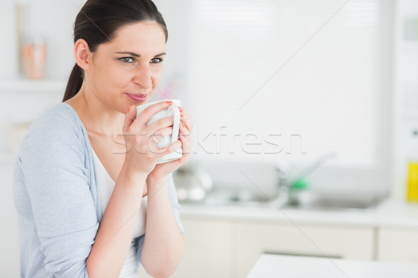 Stock photo: Thoughtful woman holding a mug in a kitchen