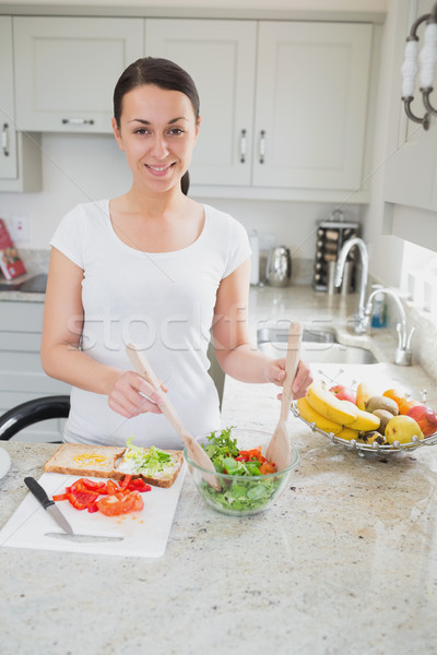 Young woman happily making lunch in kitchen Stock photo © wavebreak_media