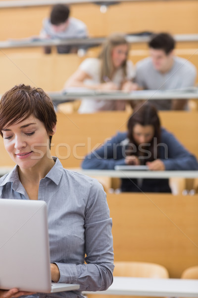 Lecturer standing while holding a laptop in lecture hall Stock photo © wavebreak_media
