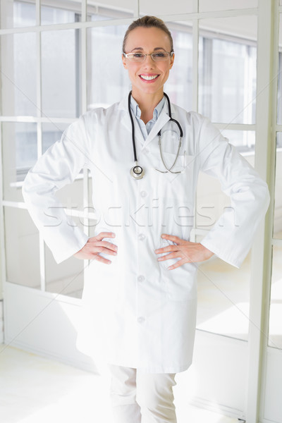 Smiling beautiful female doctor with hands on hips in hospital Stock photo © wavebreak_media