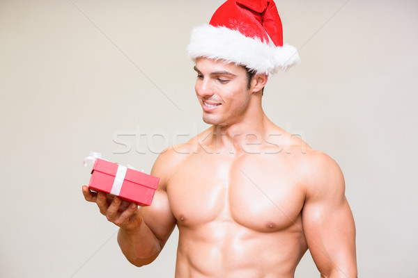 Macho man in santa hat holding gift over white background Stock photo © wavebreak_media