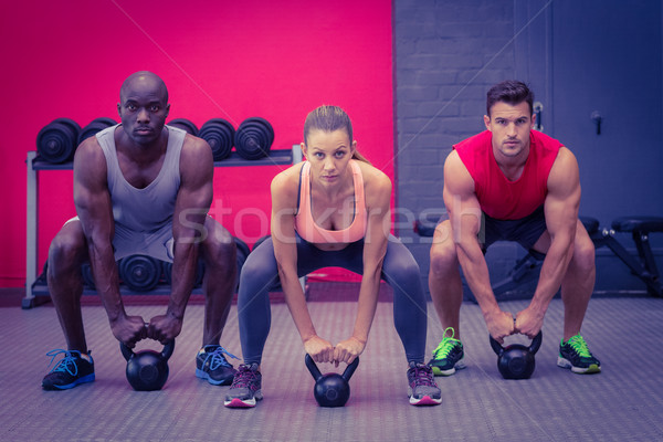 Three muscular athletes about to lift a kettle bell Stock photo © wavebreak_media