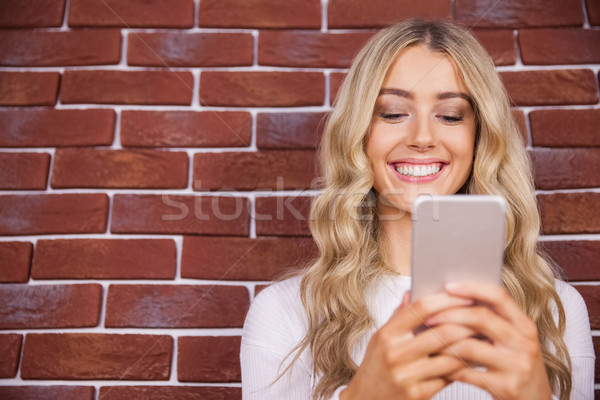 Mooie blonde vrouw glimlachend smartphone Rood baksteen Stockfoto © wavebreak_media