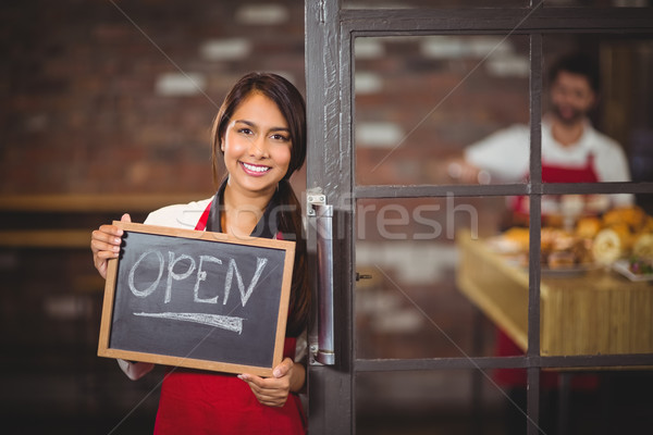 Smiling waitress showing chalkboard with open sign  Stock photo © wavebreak_media