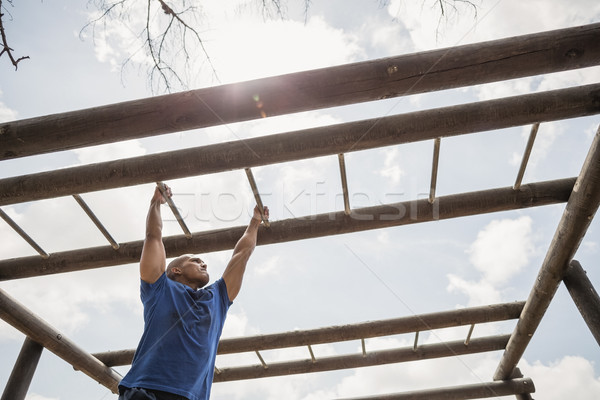 Fit man climbing monkey bars during obstacle course Stock photo © wavebreak_media