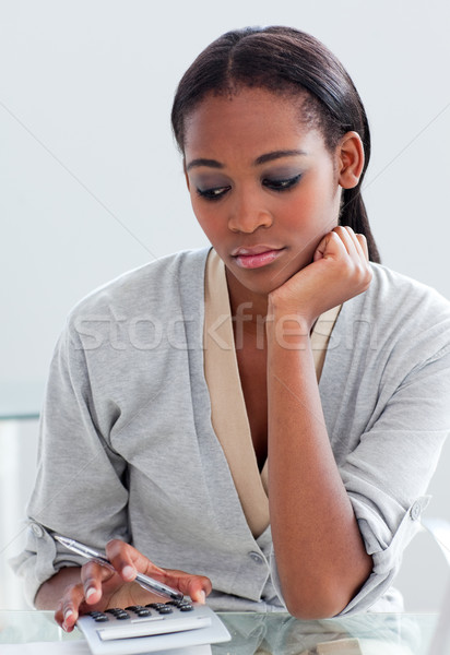 Serious businesswoman using a calculator at her desk Stock photo © wavebreak_media
