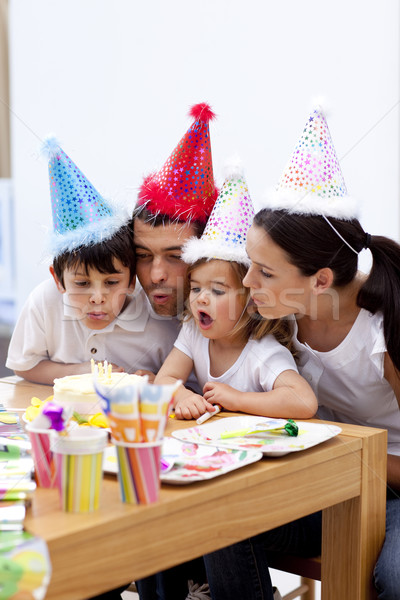 Stock photo: Little girl blowing out candles in her birthday's day with famil