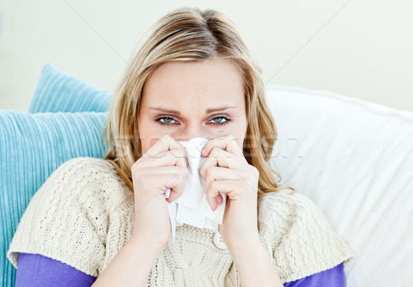 Diseased woman using a tissue sitting on a sofa Stock photo © wavebreak_media