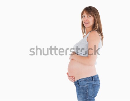 Side view of a beautiful pregnant woman caressing her belly while standing against a white backgroun Stock photo © wavebreak_media