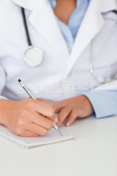 Young female doctor with a stethoscope writing on a scratchpad in her office Stock photo © wavebreak_media