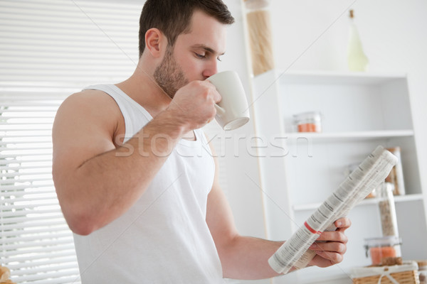 Young man drinking coffee while reading the news in his kitchen Stock photo © wavebreak_media