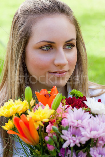 Young blonde girl holding a bunch of flowers while looking away in the countryside Stock photo © wavebreak_media