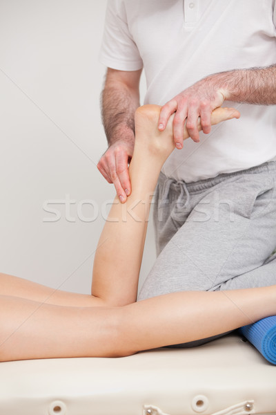 Podiatrist massaging the ankle of a woman in a room Stock photo © wavebreak_media