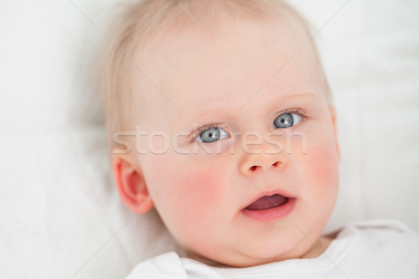 Cute baby lying while opening her mouth indoors Stock photo © wavebreak_media