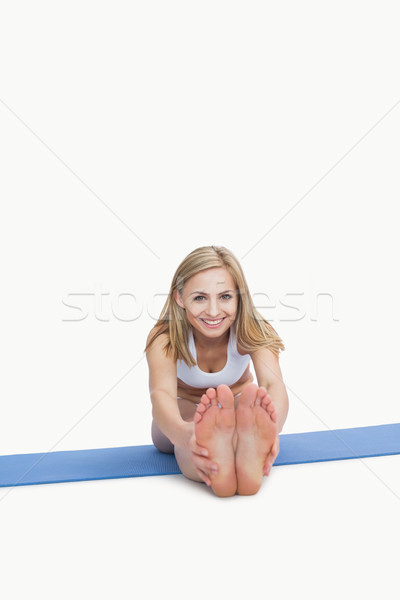 Stock photo: Portrait of happy woman performing stretching exercise on yoga m