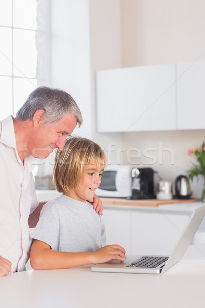 Stock photo: Child and grandfather looking at laptop with smile