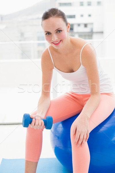 Stock photo: Fit brunette lifting blue dumbbell