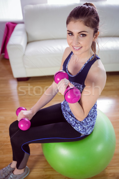 Fit woman lifting dumbbells on exercise ball Stock photo © wavebreak_media