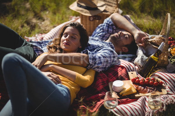 Stock photo: Young couple relaxing on picnic blanket at olive farm