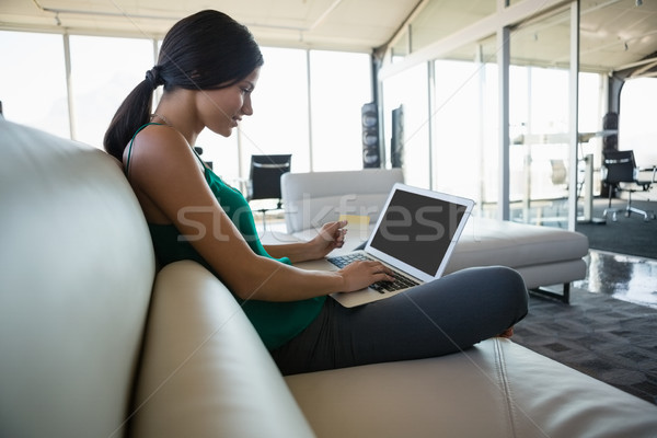 Vedere laterala femeie folosind laptop canapea birou tineri Imagine de stoc © wavebreak_media