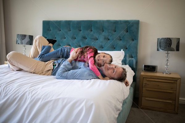 Smiling father and daughter lying on bed in bedroom Stock photo © wavebreak_media