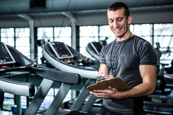 Muscular trainer writing on clipboard Stock photo © wavebreak_media