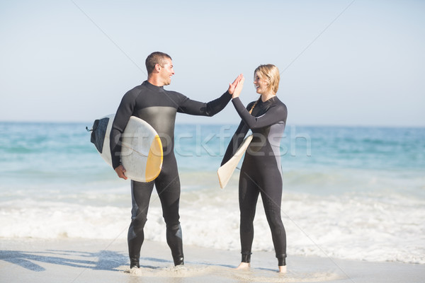 Casal prancha de surfe high five outro praia Foto stock © wavebreak_media