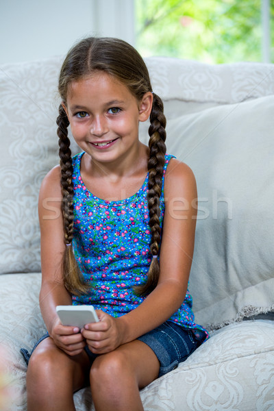 Mosolyog lány mobiltelefon ül kanapé portré Stock fotó © wavebreak_media