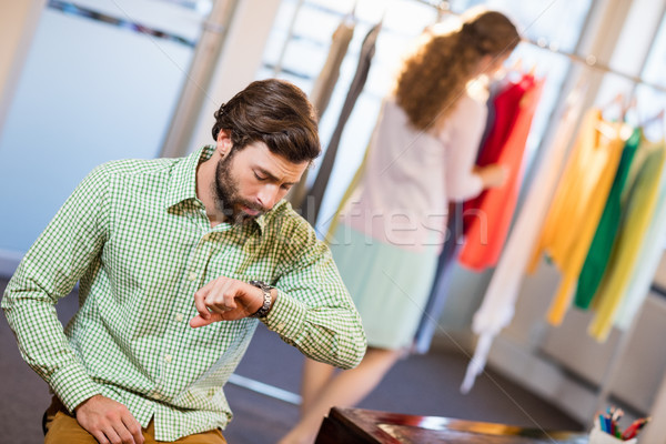 Bored man waiting his wife while woman by clothes rack Stock photo © wavebreak_media