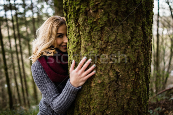 Beautiful woman hiding behind tree trunk in forest Stock photo © wavebreak_media
