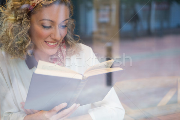 Stock photo: Smiling woman reading book seen through cafe window