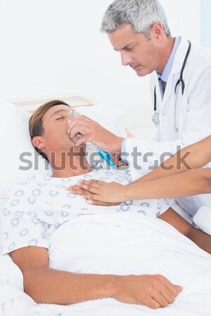 Young doctor putting oxygen mask on a senior patient  Stock photo © wavebreak_media