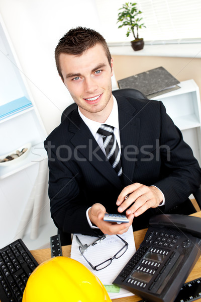 Positive businessman using his calculator looking at the camera Stock photo © wavebreak_media