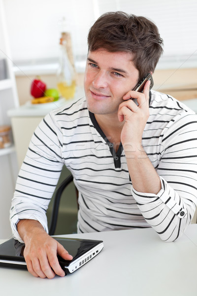 Ravi homme parler téléphone utilisant un ordinateur portable cuisine [[stock_photo]] © wavebreak_media