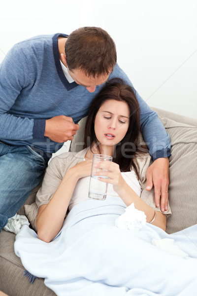 Attentive man bringing a glass of water to his sick grilfriend lying on the sofa Stock photo © wavebreak_media