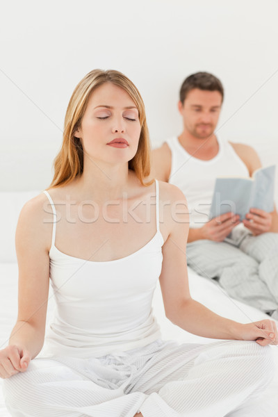 Woman practicing yoga while her husband is reading on the bed Stock photo © wavebreak_media