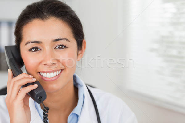 Stock photo: Lovely female doctor on the phone and posing in her office