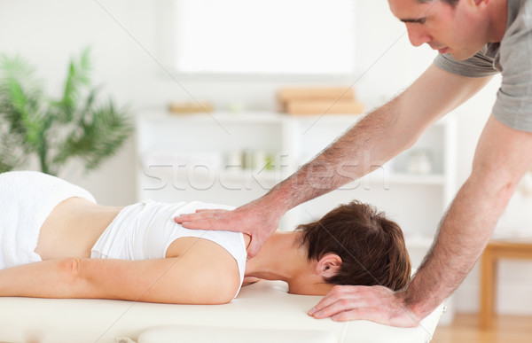 Stock photo: A masseur is massaging a woman's back 
