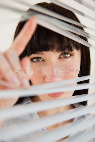 A woman opens her blinds to look through the window into the camera Stock photo © wavebreak_media