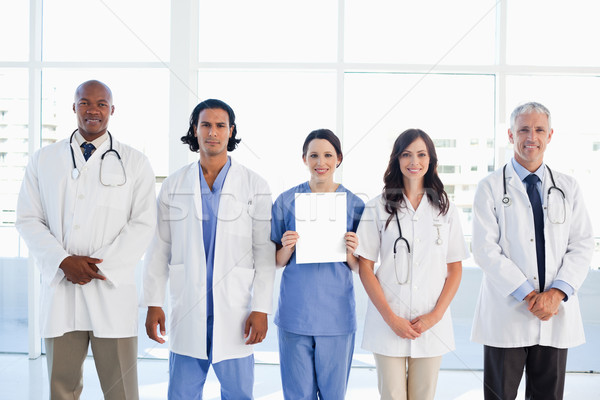 Medical people surrounding a new intern which is holding a blank sheet Stock photo © wavebreak_media