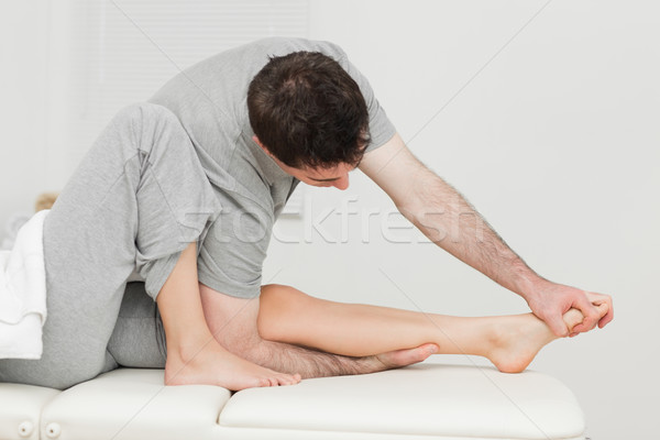 Brunette osteopath stretching a foot in a medical room Stock photo © wavebreak_media