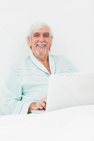 ストックフォト: 笑みを浮かべて · 男 · ベッド · 歳の男性 · ノートパソコン · コンピュータ
