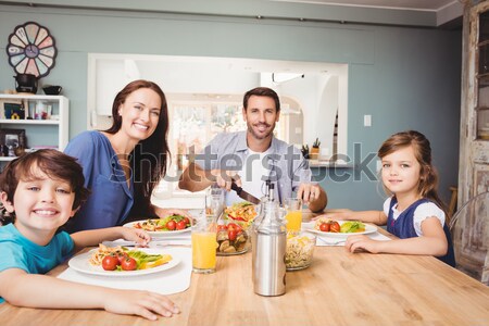 Family smiling at the camera at dinner table Stock photo © wavebreak_media