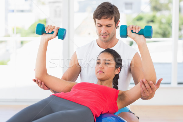 Instructor assisting woman with dumbbell weights Stock photo © wavebreak_media
