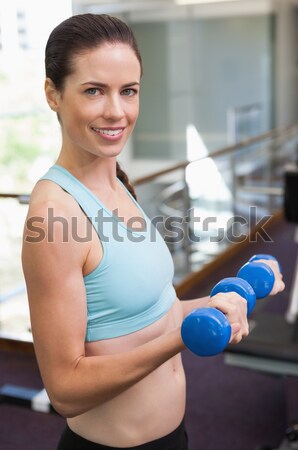 Fit brunette lifting blue dumbbells Stock photo © wavebreak_media