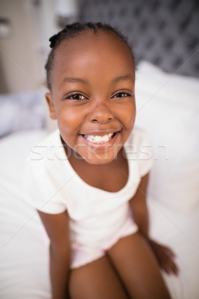 Portrait of smiling girl sitting on bed Stock photo © wavebreak_media